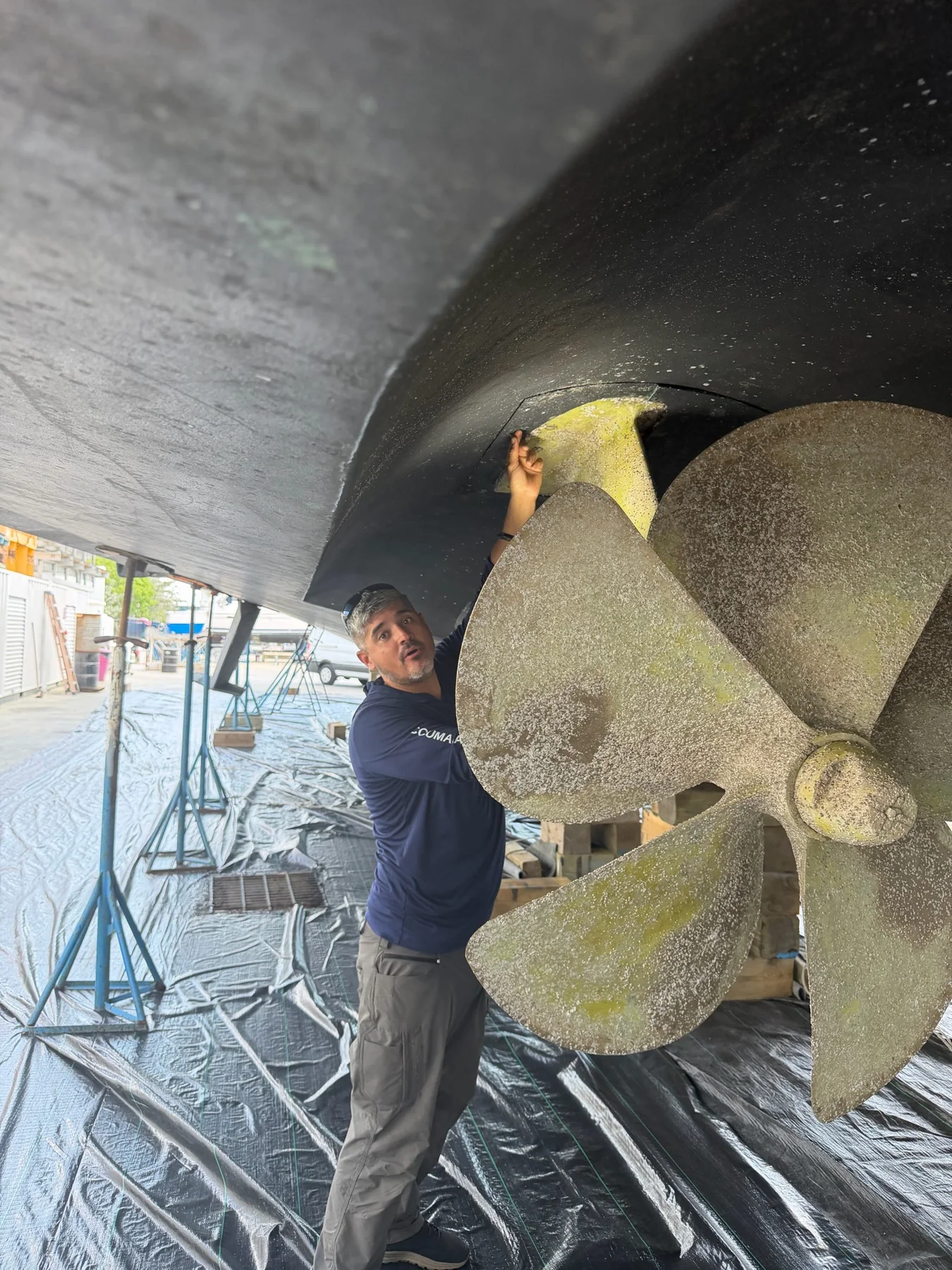 Marine technician inspecting a vessel hull and propeller in a boatyard