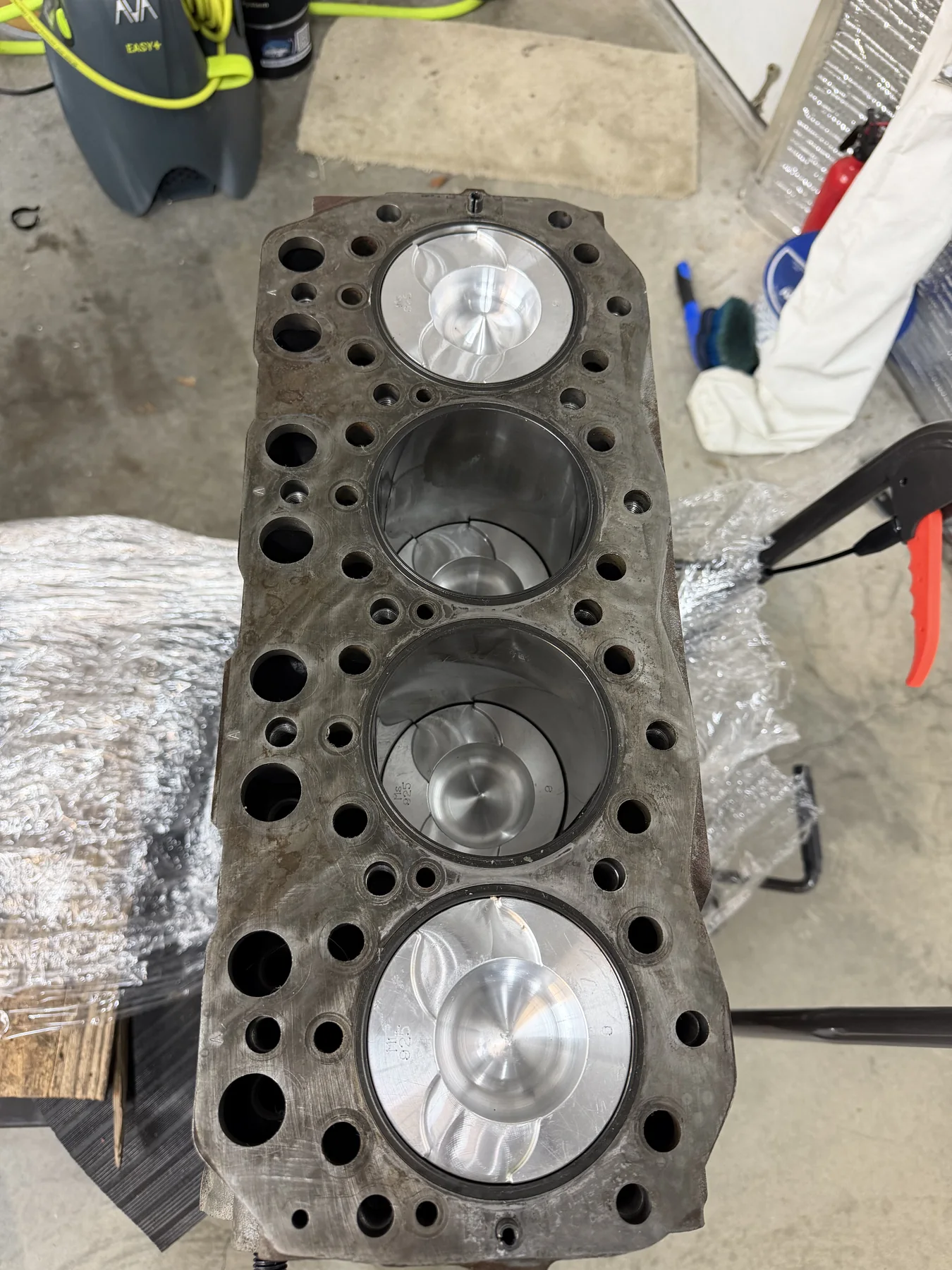 Four-cylinder engine block with outer pistons visible and inner cylinders open.