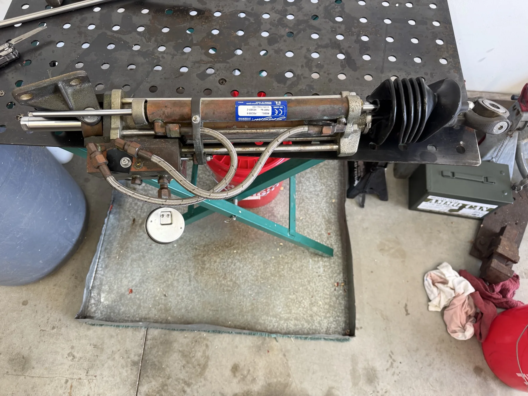 Hydraulic steering cylinder with hoses and pressure gauge on a workbench