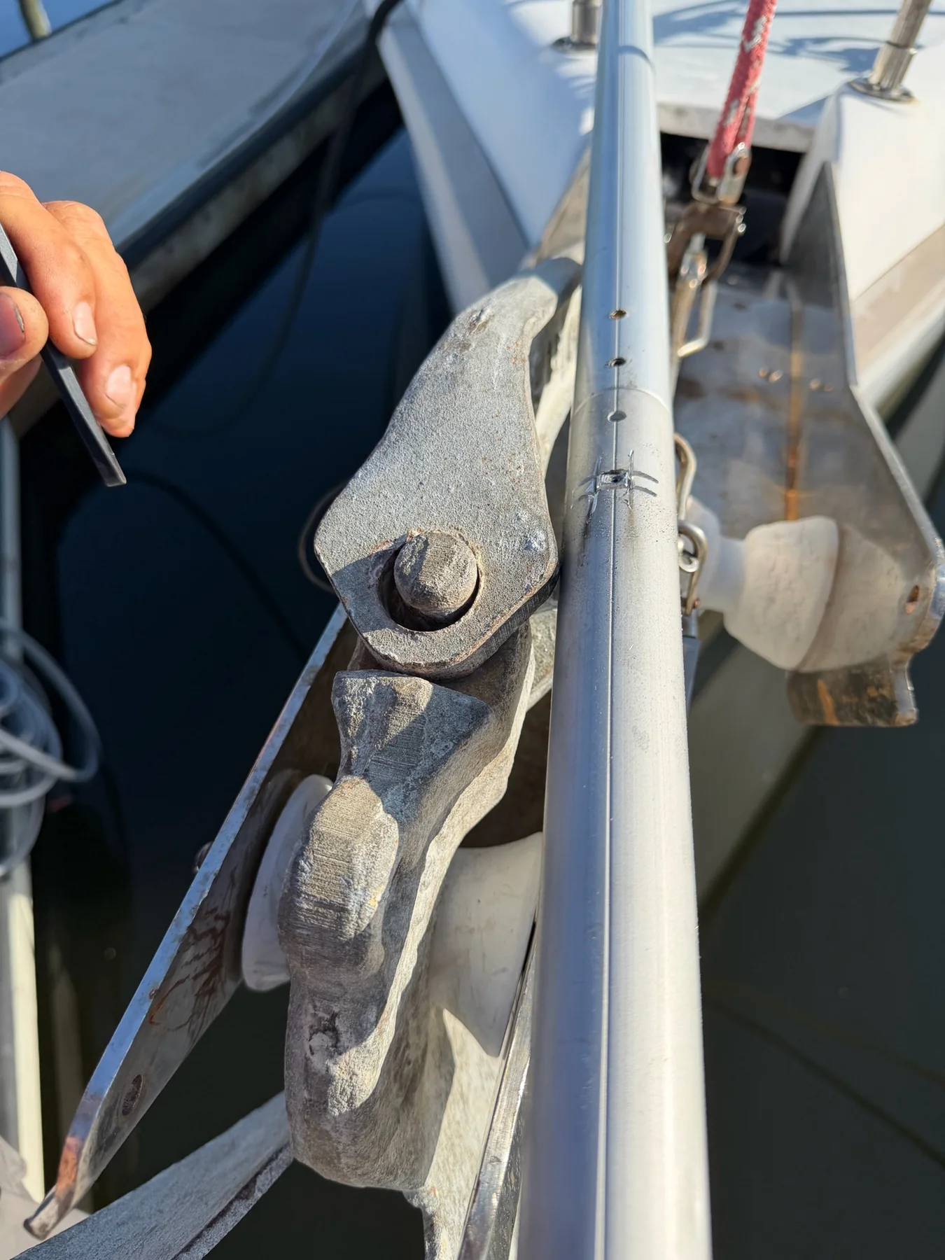 Corroded metal toggle and aluminum furling extrusion being inspected at a sailboat bow